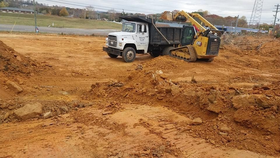 A dump truck and yellow track loader working on a construction site, moving dirt.