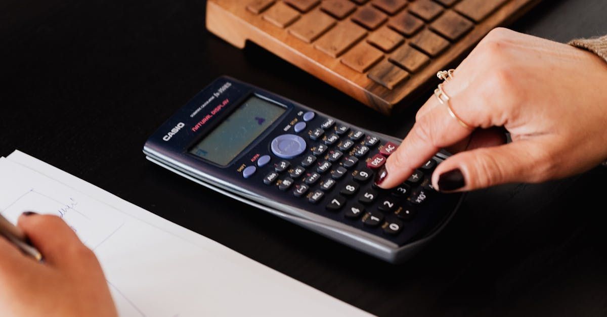 Person using calculator for bookkeeping with keyboard in background