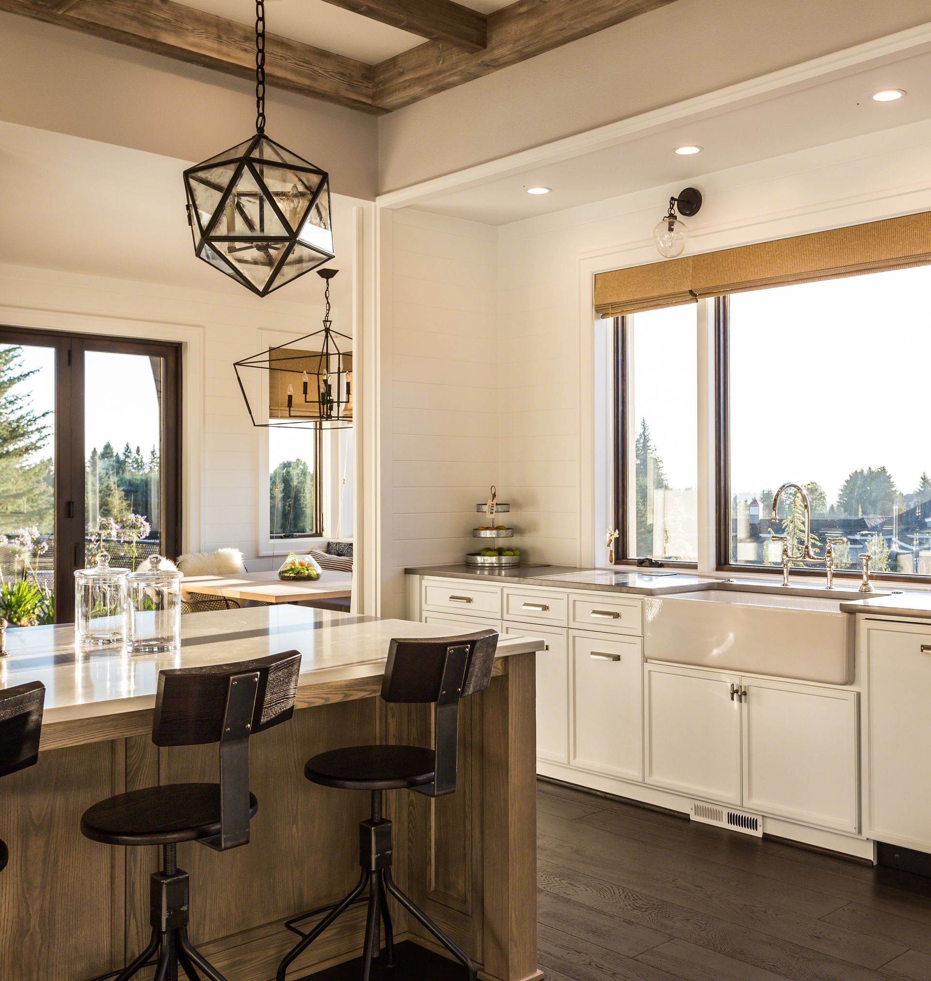 Bright modern kitchen with white cabinets, wood island, bar stools, and large windows with city views Bright modern kitchen with white cabinets, wood island, bar stools, and large windows with city views