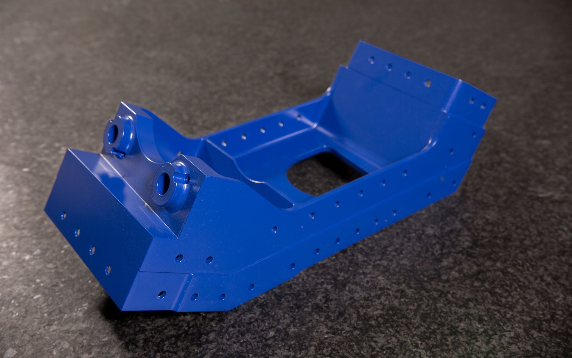 A blue metal object is sitting on a black surface.