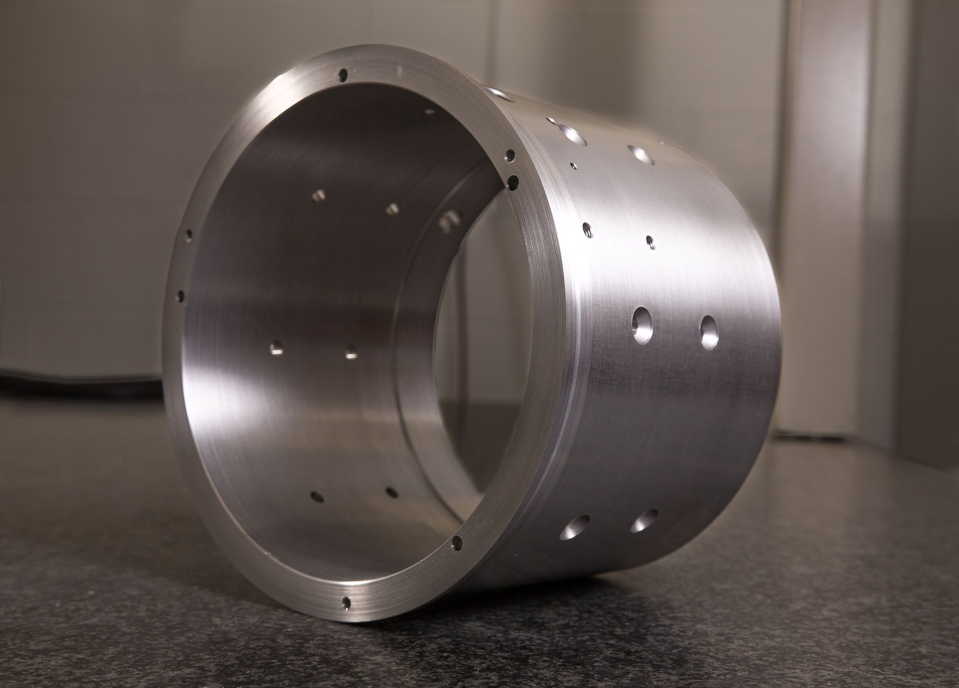 A metal cylinder with holes in it is sitting on the floor