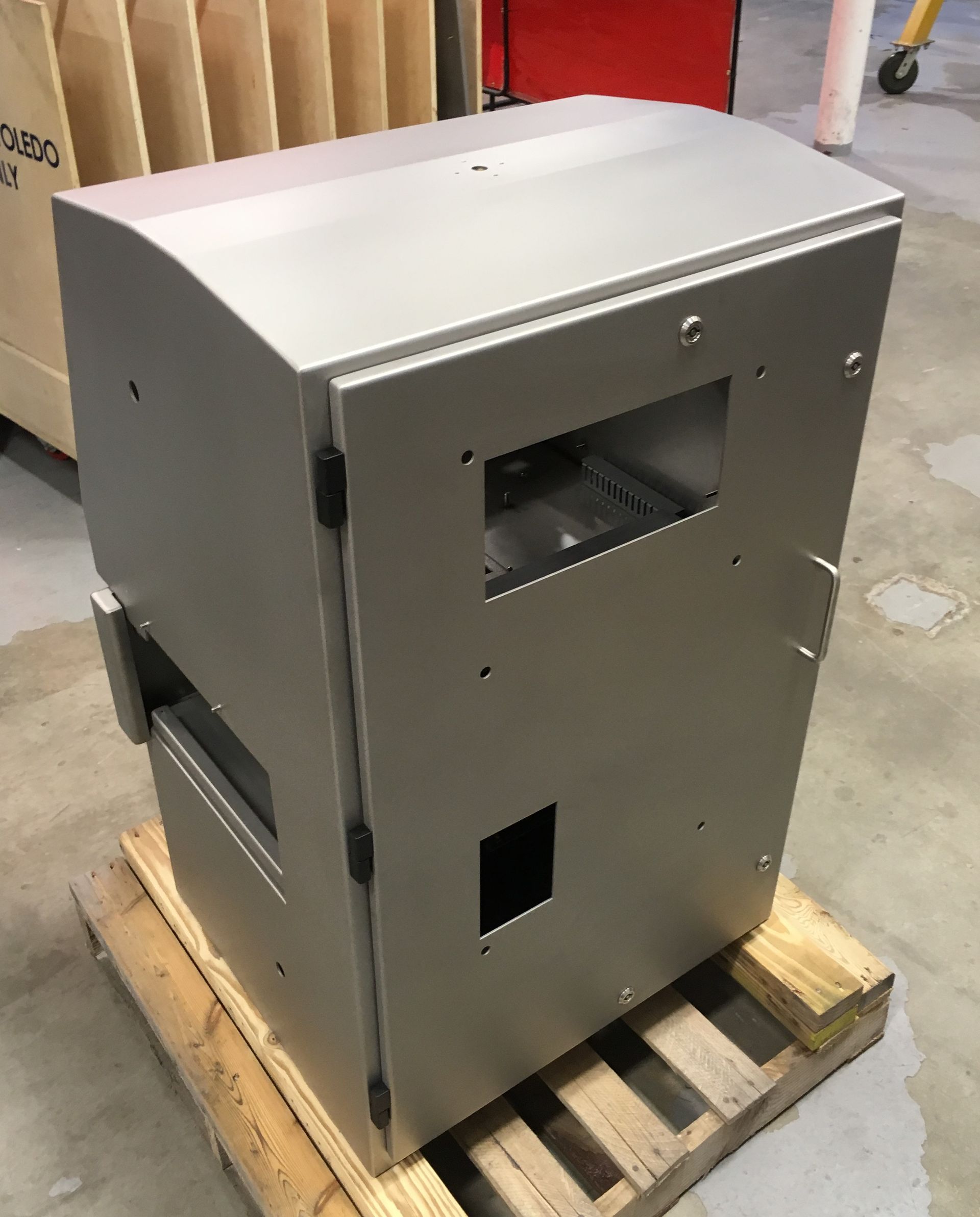 A stainless steel box is sitting on top of a wooden pallet.