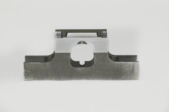 A piece of metal with a hole in the middle on a white surface.