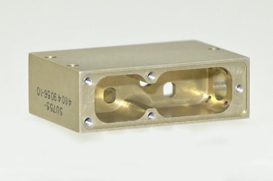 A metal block with two holes in it is sitting on a white surface.