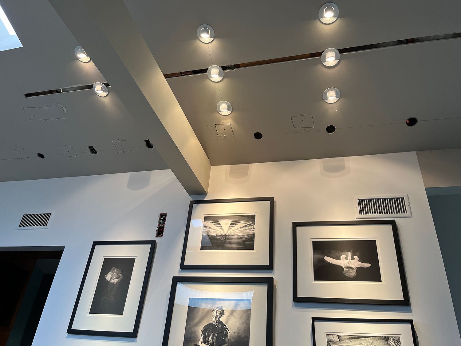 Gallery wall with framed black and white photos, ceiling spotlights, and a white wall.