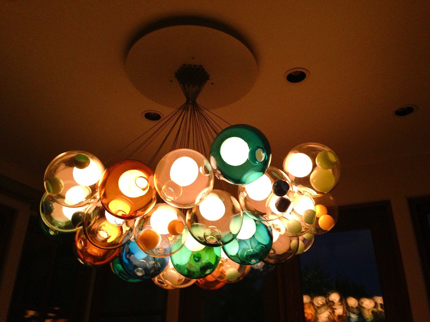 A modern chandelier with colorful glass globes, illuminating a room.