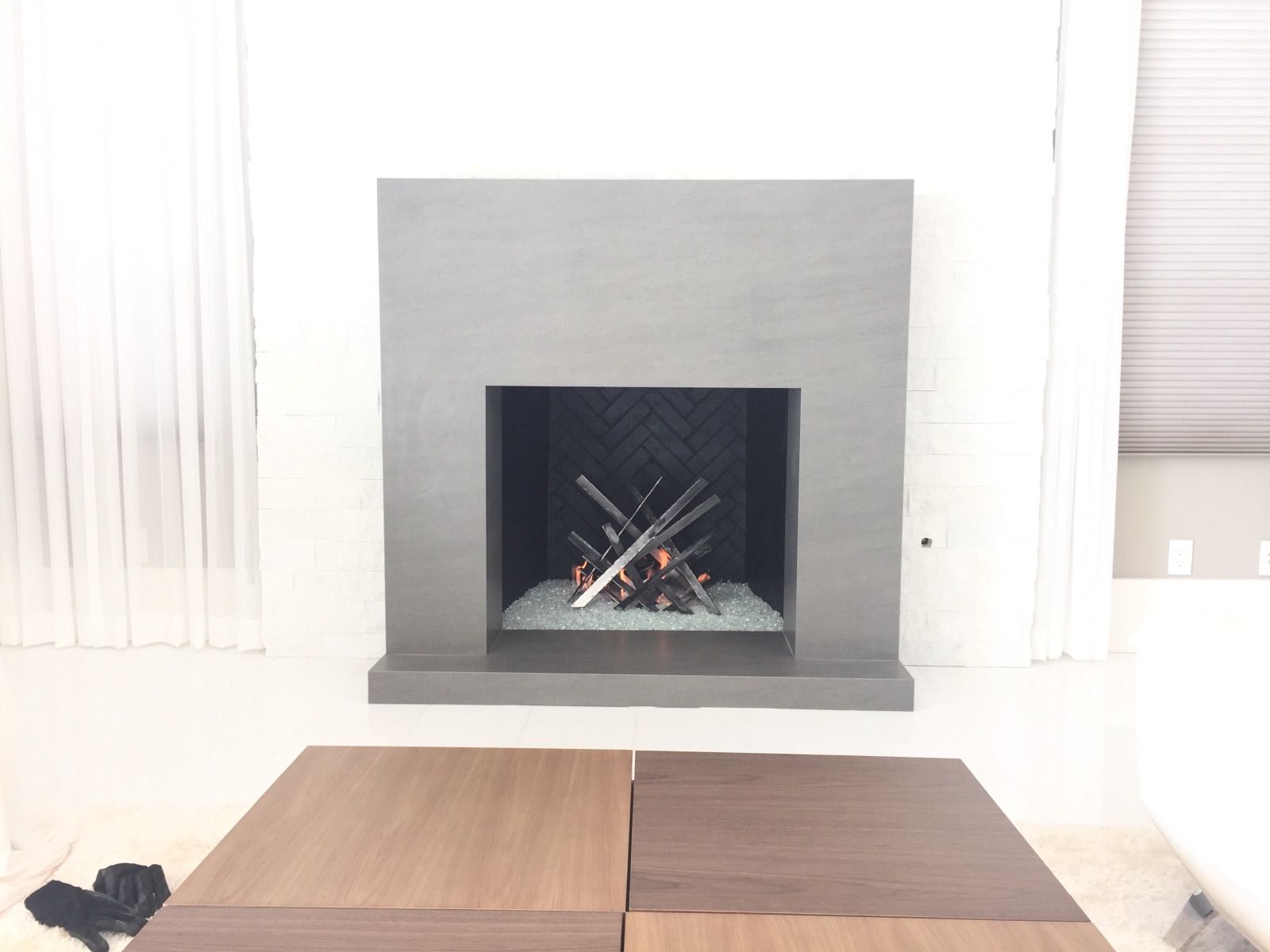 Gray modern fireplace with a burning fire and dark wooden table.