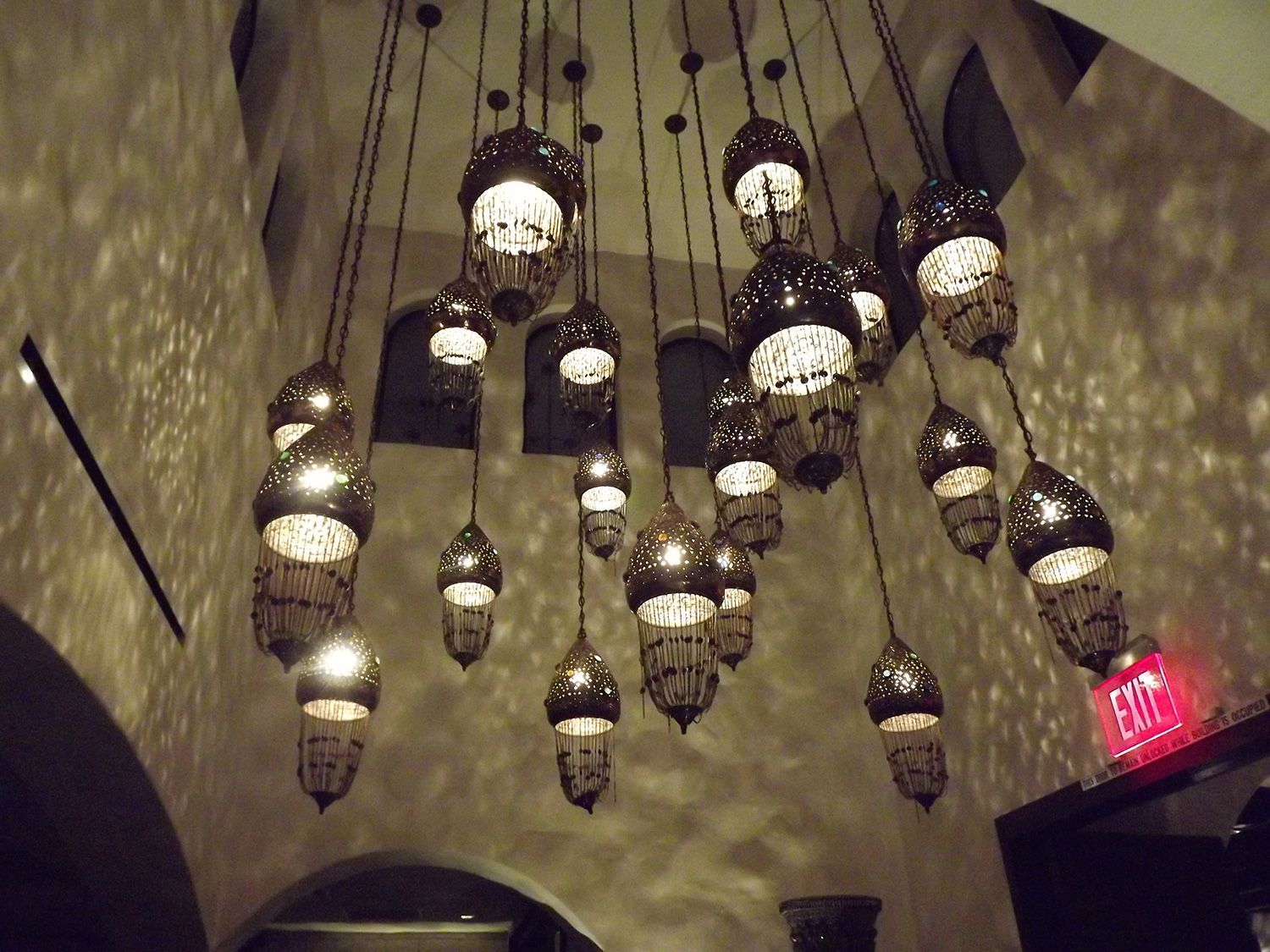 Ornate pendant lights hang in a dim room, casting shadows on the curved walls.