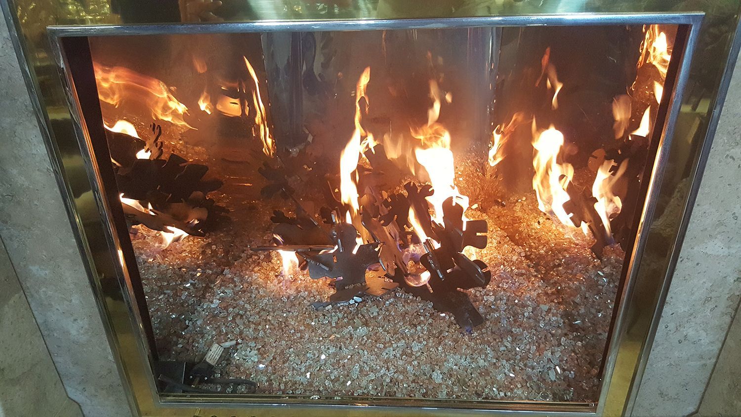 Fireplace with burning flames and glass rock bed.