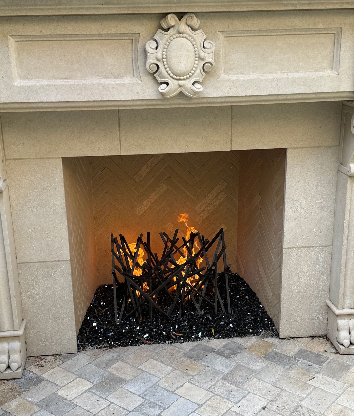 Fireplace with burning black logs, surrounded by black glass and a stone facade.