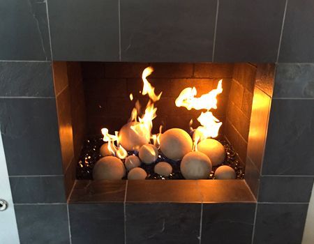 Fireplace with flames, ceramic spheres, and black tile surround.