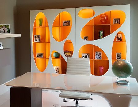 Modern office with white desk, orange built-in shelving unit, and a green globe.