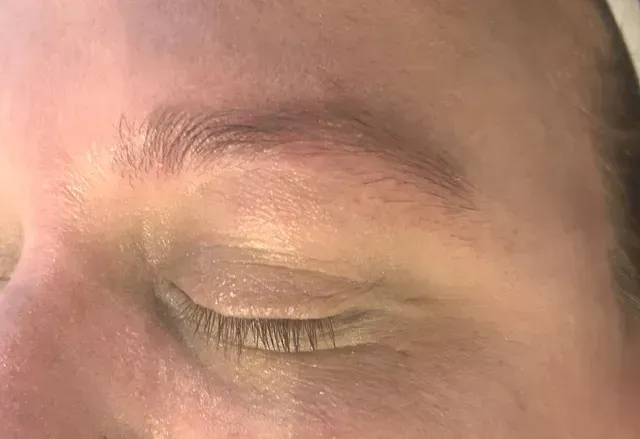 Close-up of a person's closed eye and eyebrow; skin is visible; soft focus.