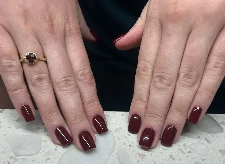 Hands with square-shaped nails painted dark red.