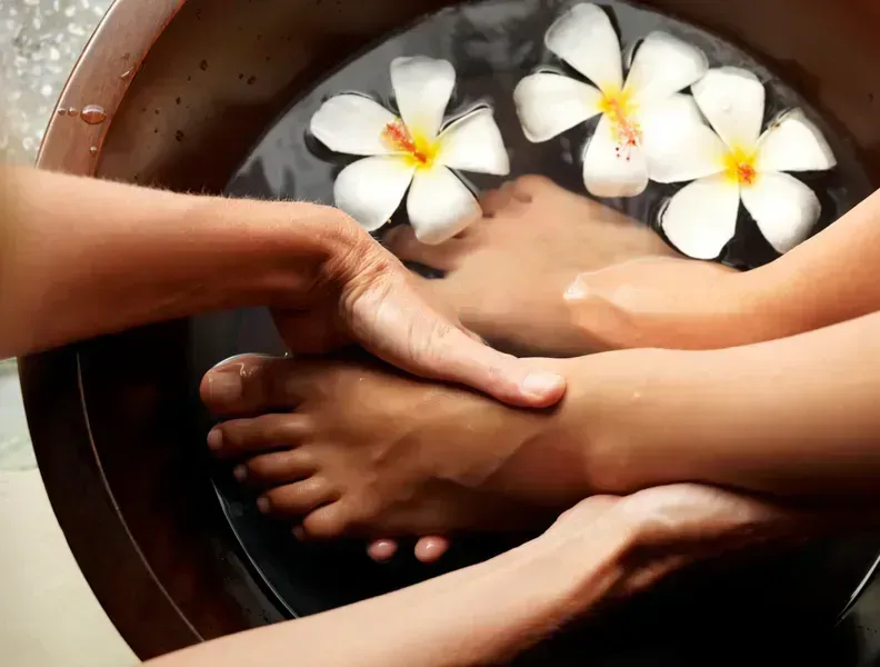 A woman's feet are on a plate with candles and flowers
