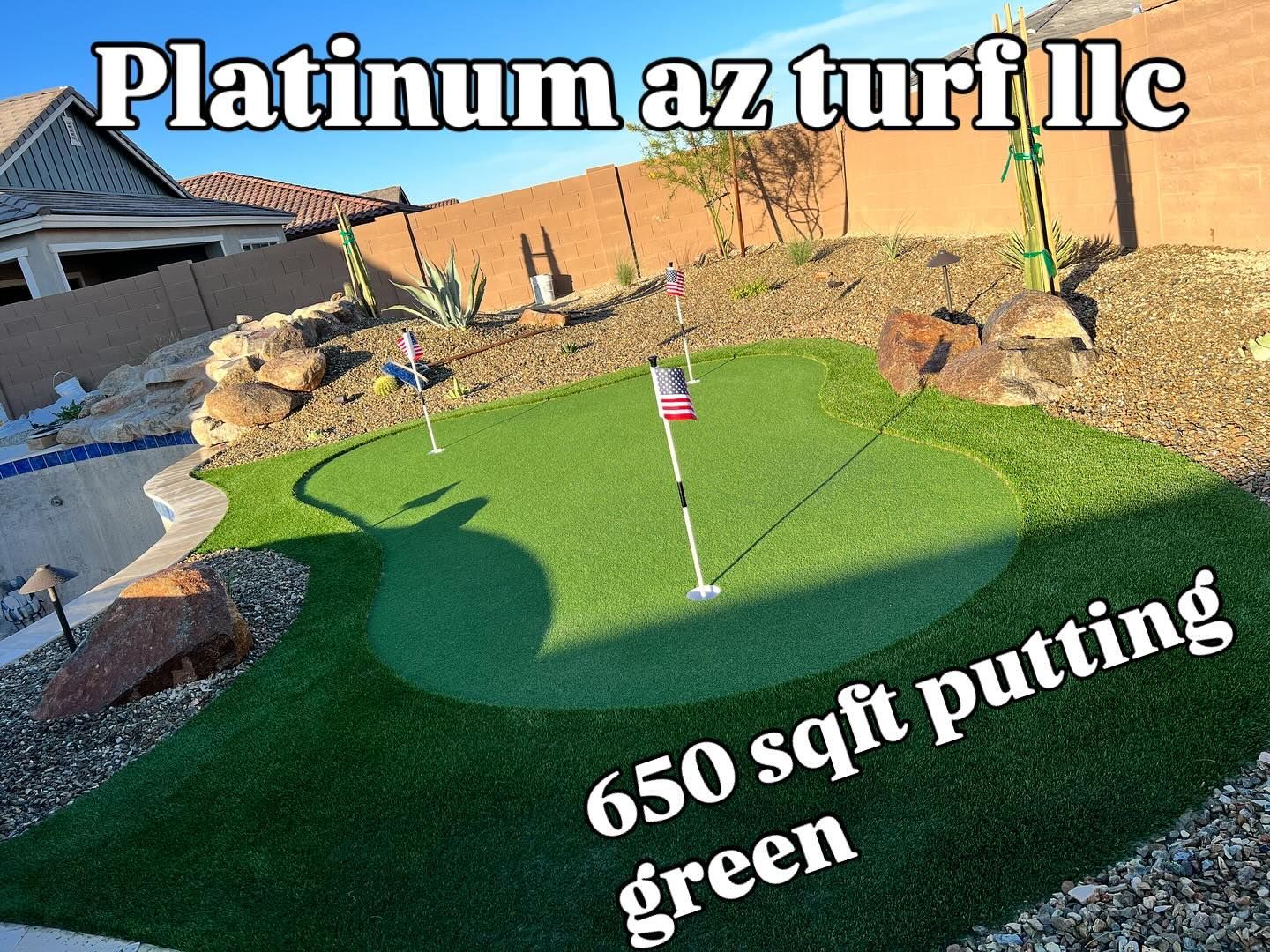 A 650-square-foot backyard putting green with two flagsticks, surrounded by desert landscaping and rocks.