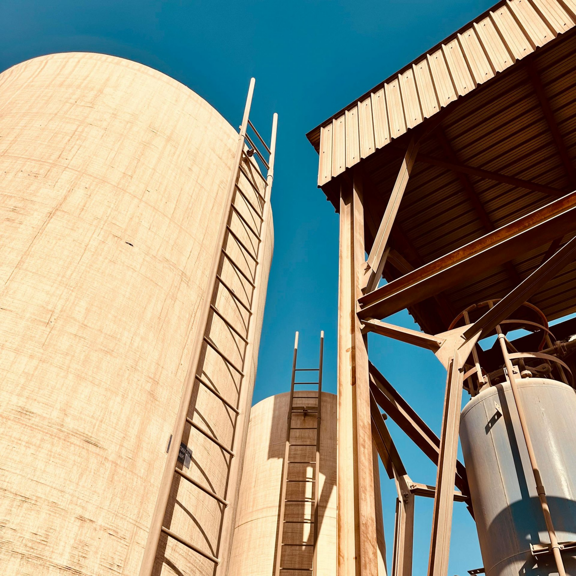 Silos di cemento e una struttura metallica contro un cielo azzurro brillante.