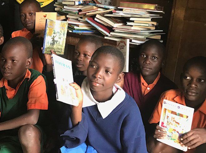 a group of children are sitting on the floor reading books .