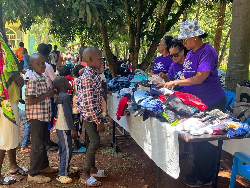 a group of people are standing around a table with clothes on it .