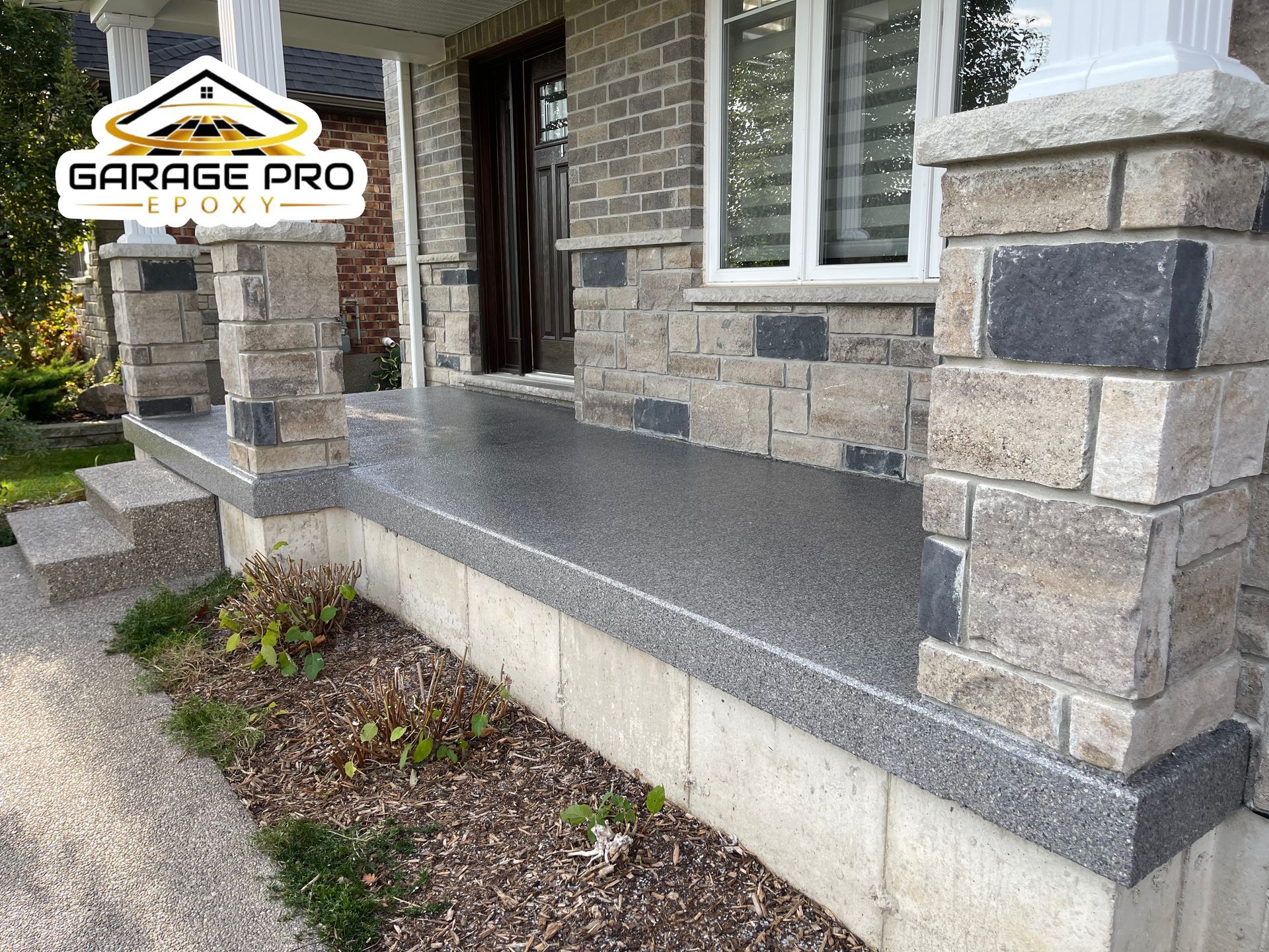 The front porch of a brick house with a garage pro logo on it.