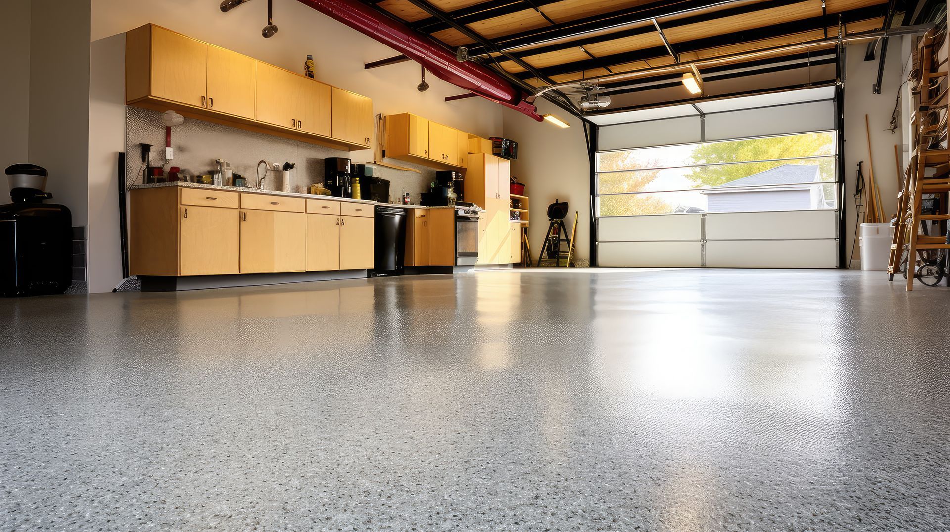 Garage interior with a shiny, speckled floor, cabinets, and an open garage door.