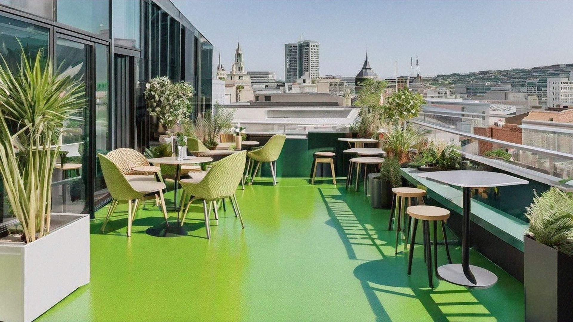There are tables and chairs on the roof of a building.