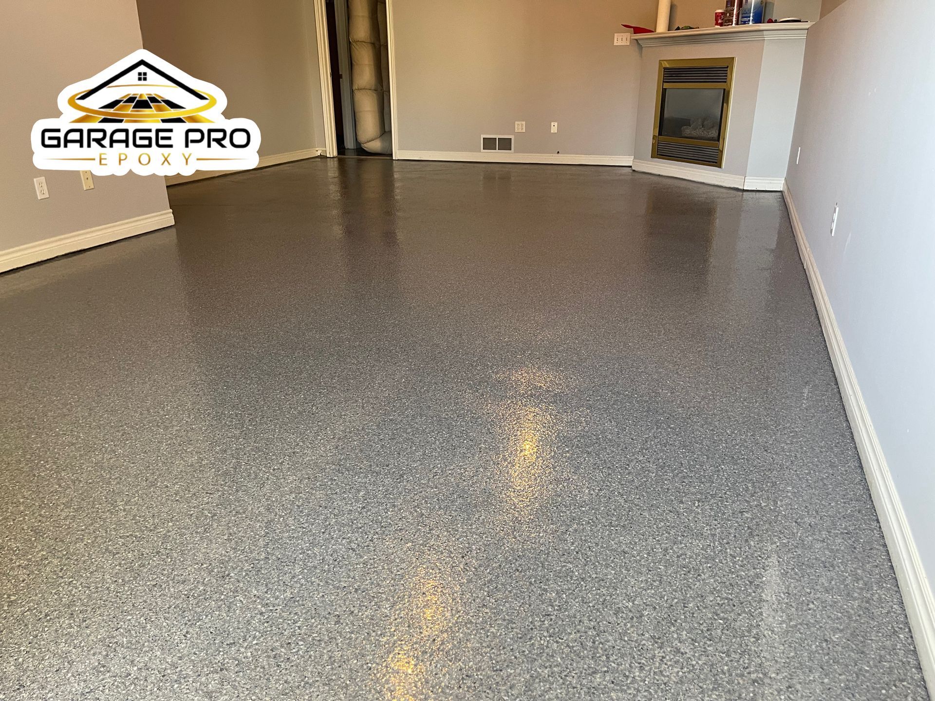 A living room with a fireplace and a garage pro logo on the floor.