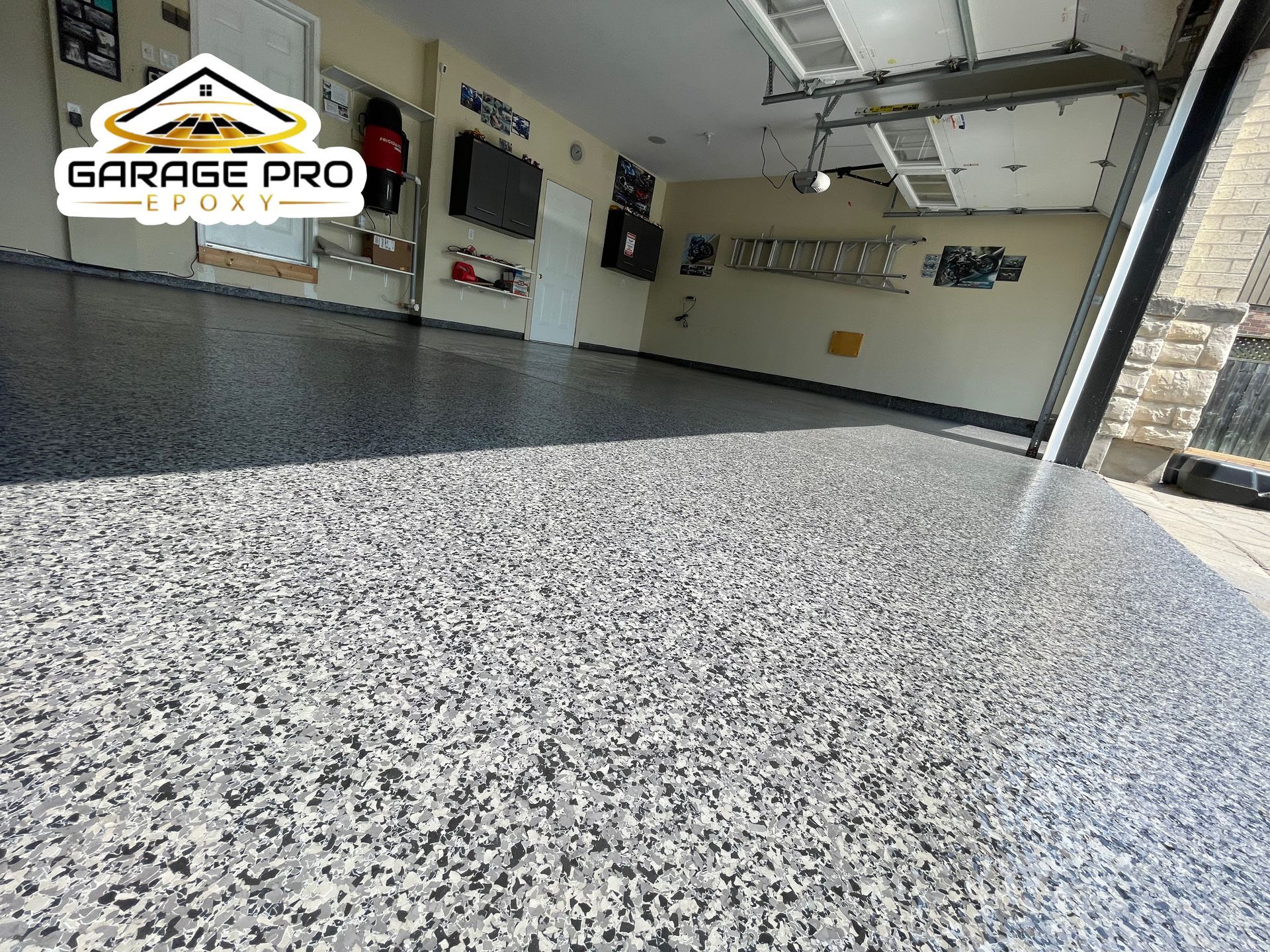 A garage with a concrete floor and a garage door open.