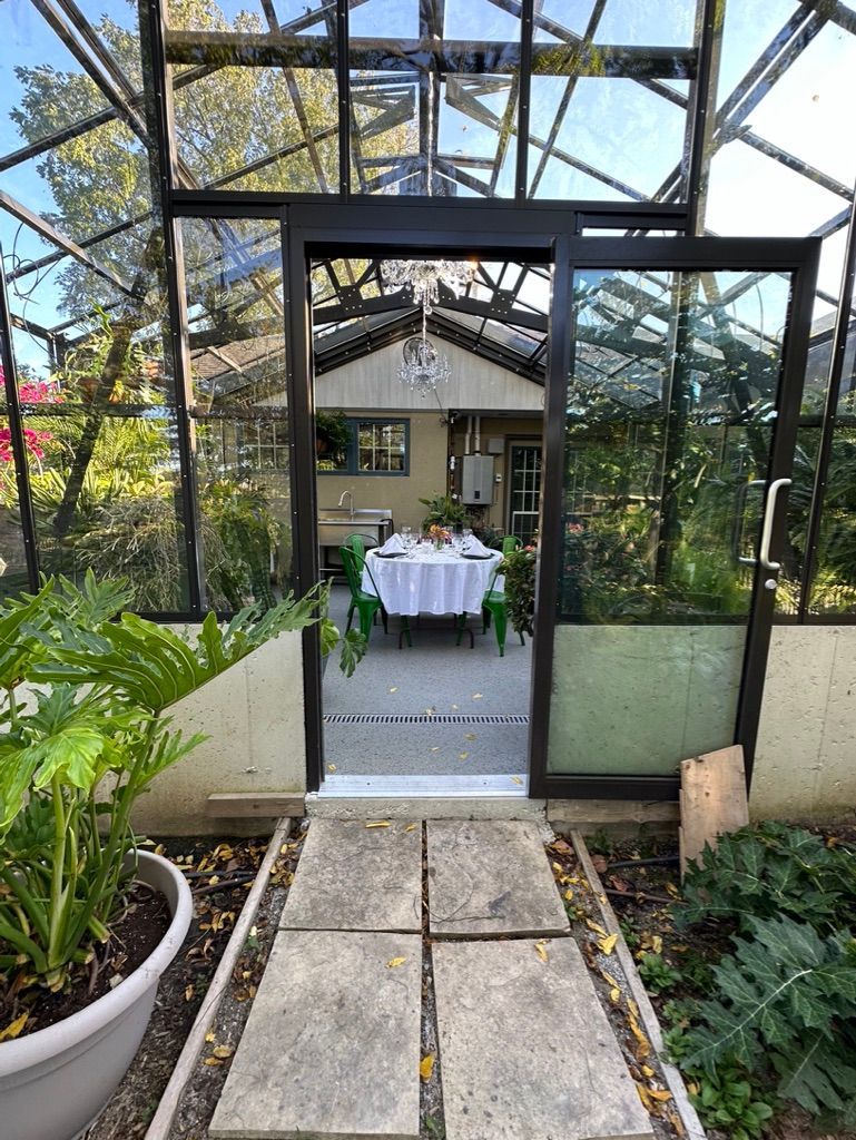 A greenhouse with a table and chairs inside of it.