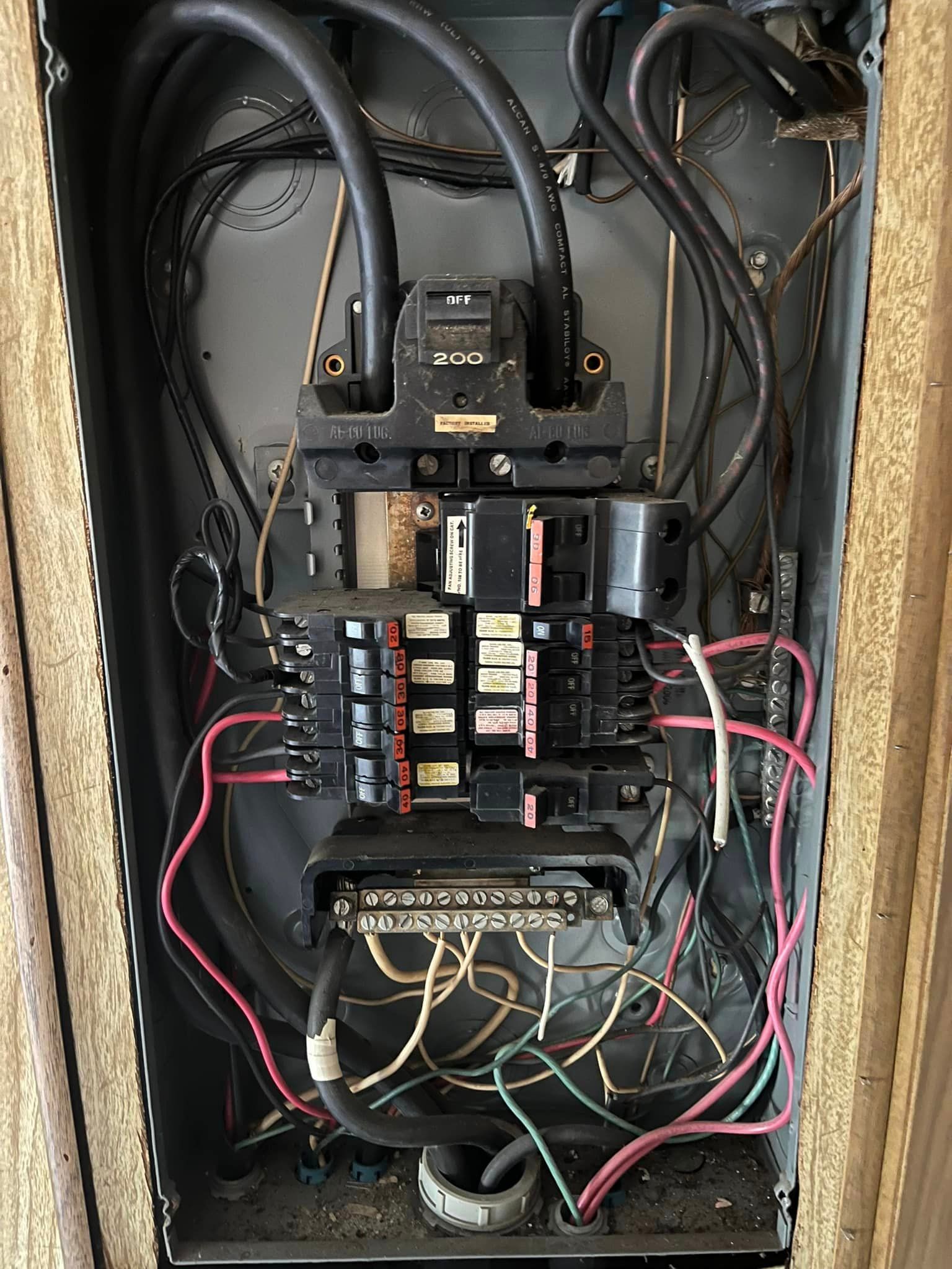 The inside of a electrical box with a lot of wires coming out of it.