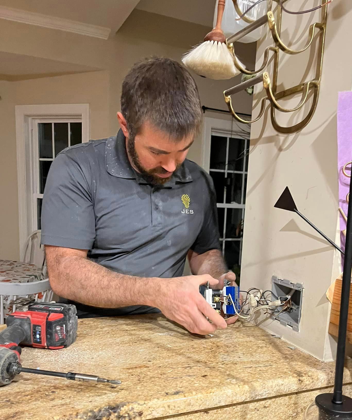 A man is sitting at a table working on an electrical outlet.