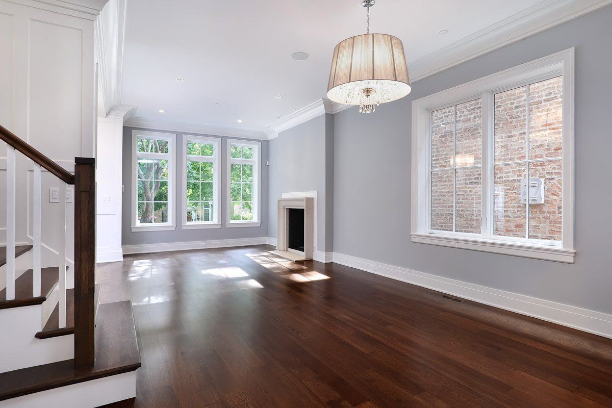 An empty living room with hardwood floors , stairs and a fireplace.