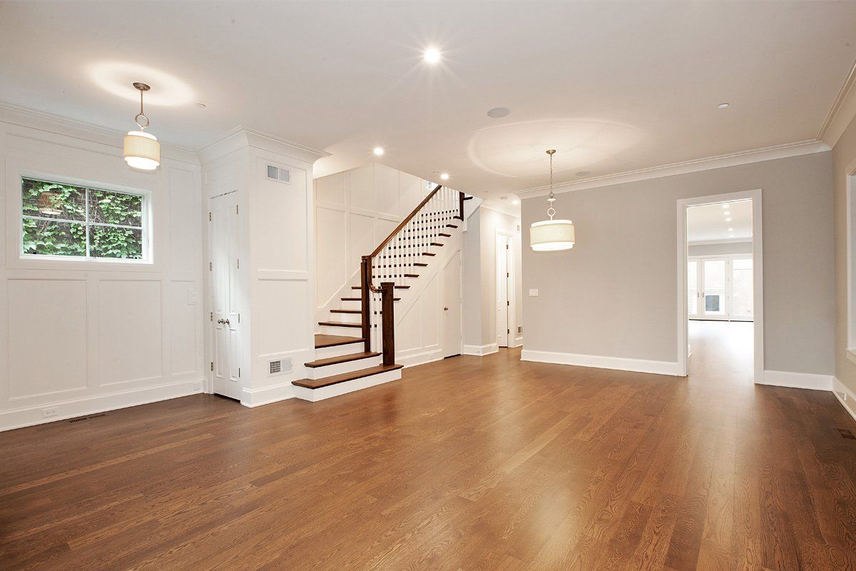 An empty living room with hardwood floors and a staircase.