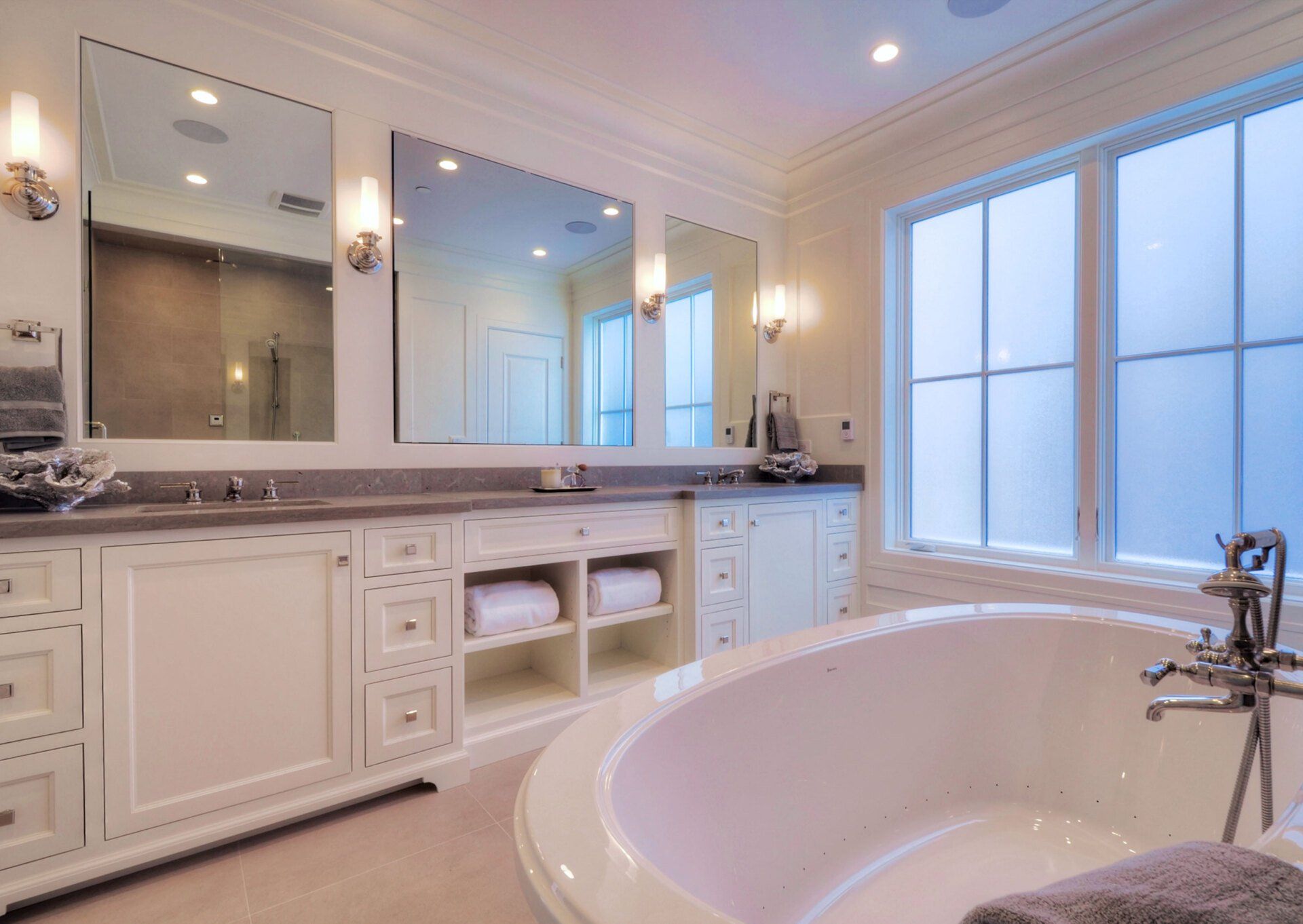 A bathroom with two sinks , a tub and two mirrors.