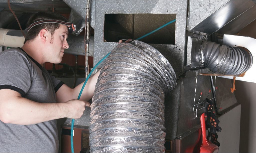 Technicien nettoyant un conduit de ventilation.