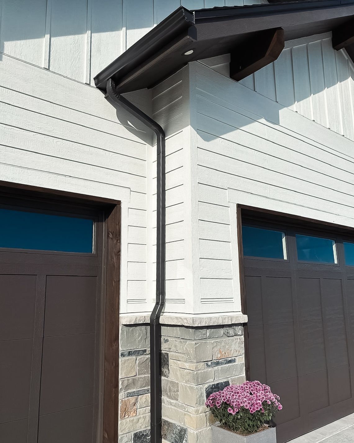 A house with two garage doors and a gutter on the side of it