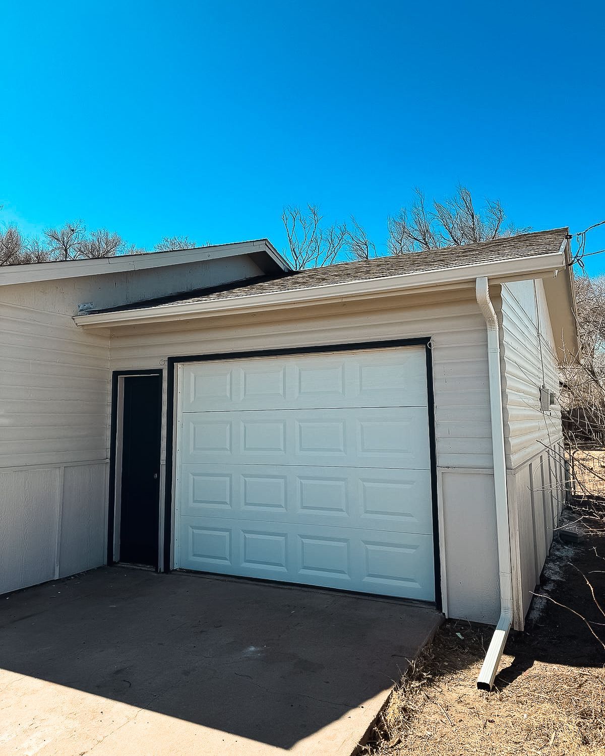 A white garage with a white garage door and a blue sky in the background.