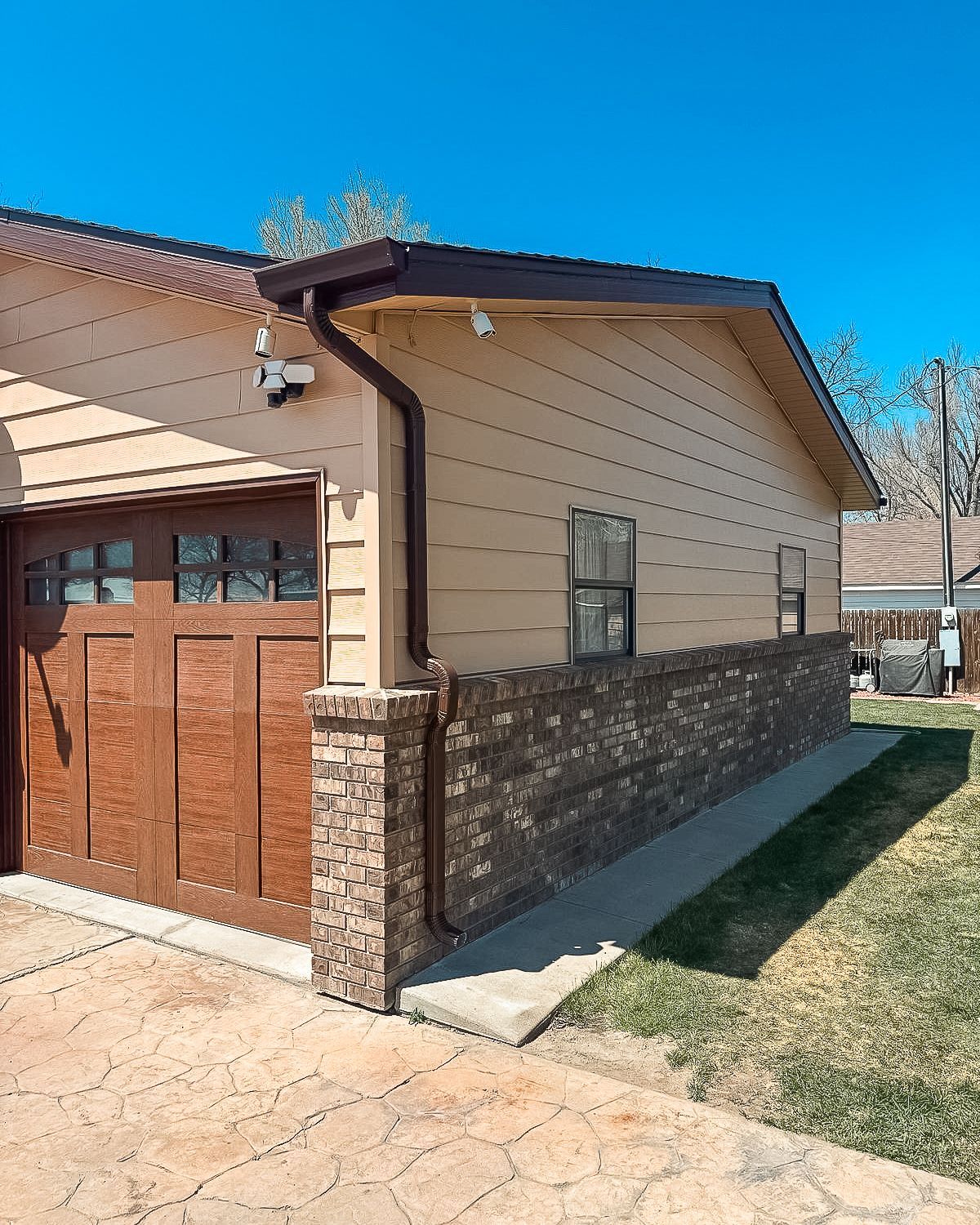 A house with a brown garage door and a brick wall
