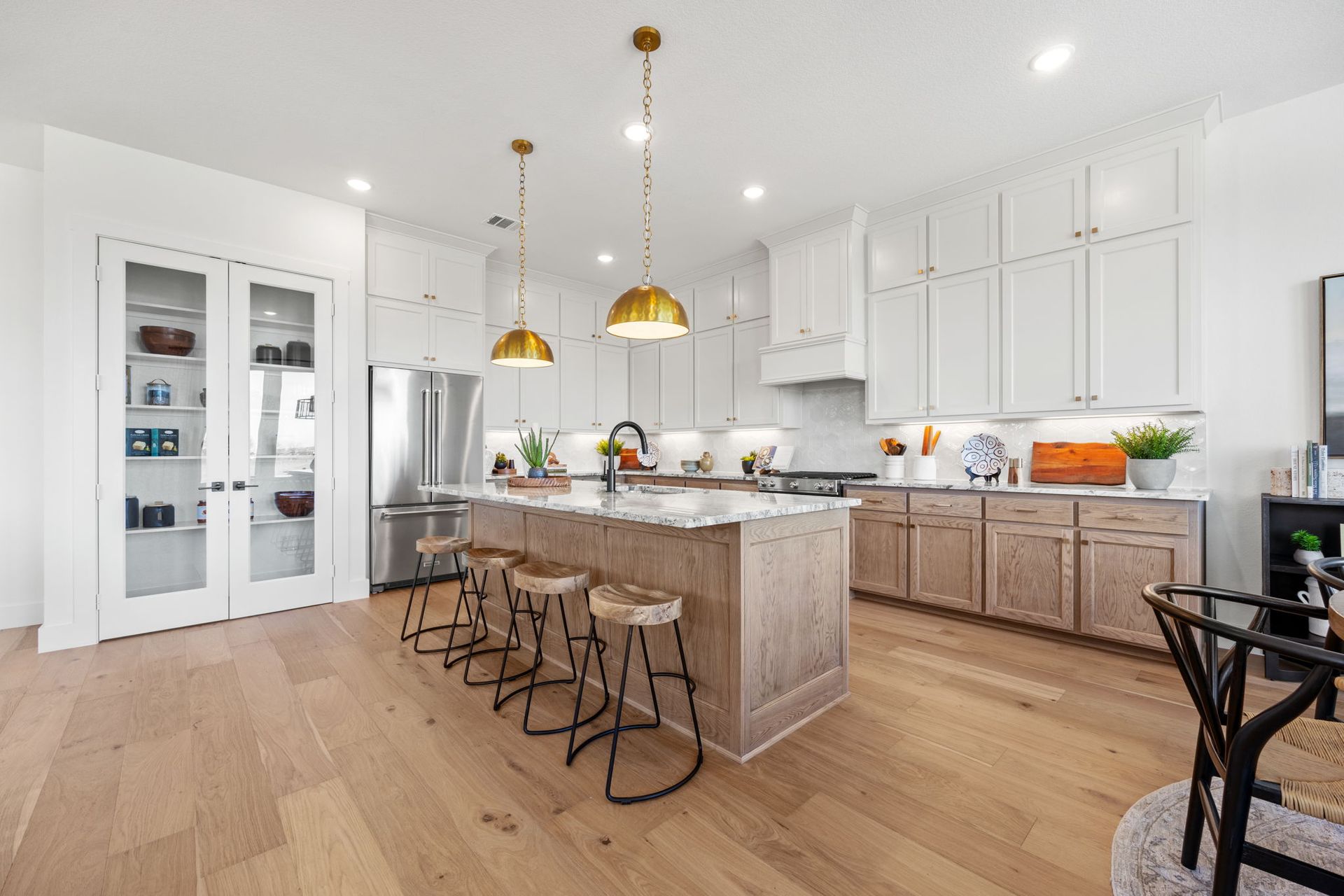 Modern kitchen with light wood cabinets, island, stainless steel appliances, and gold pendant lights.