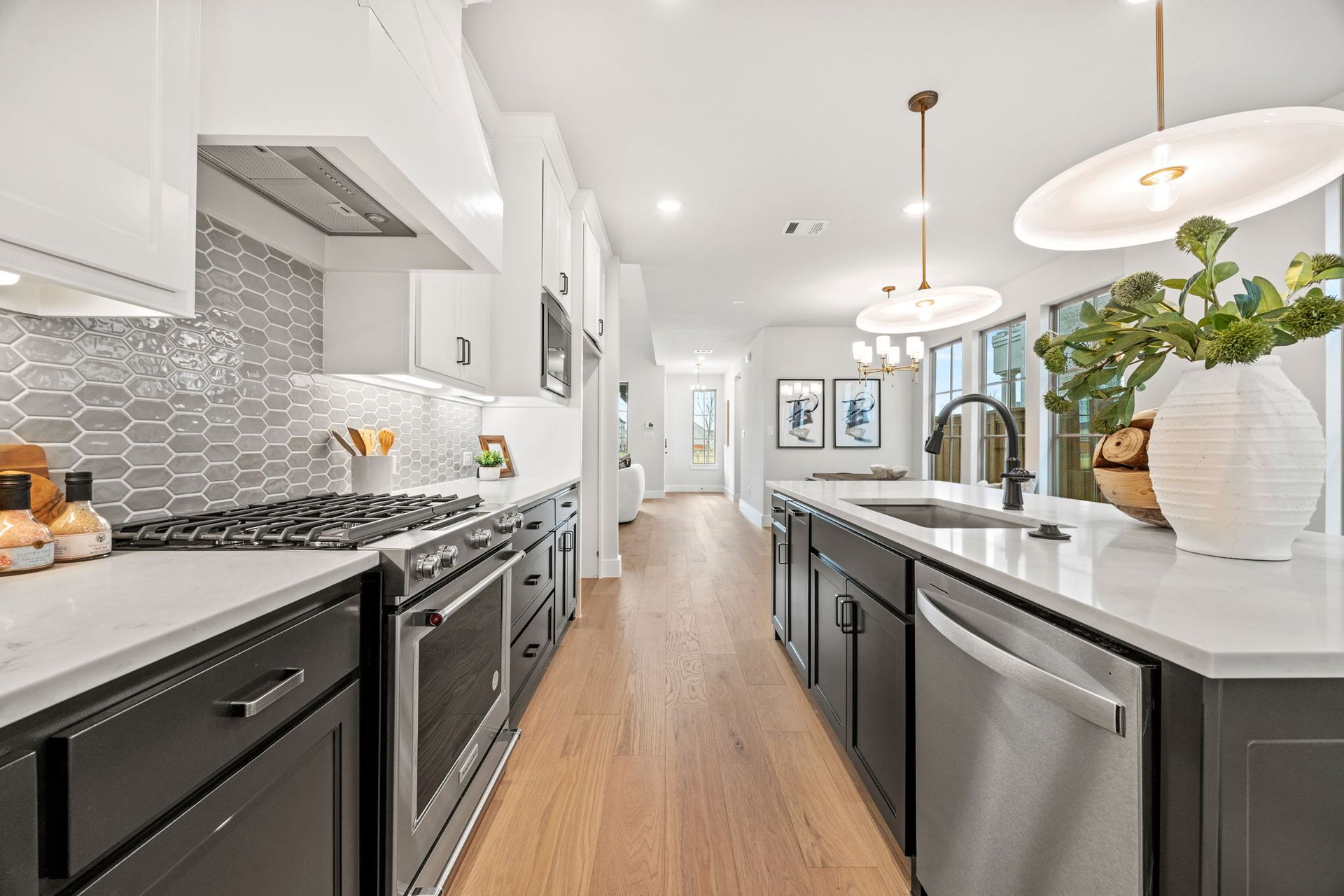 Modern kitchen with white and dark gray cabinets, stainless steel appliances, and wood floors.