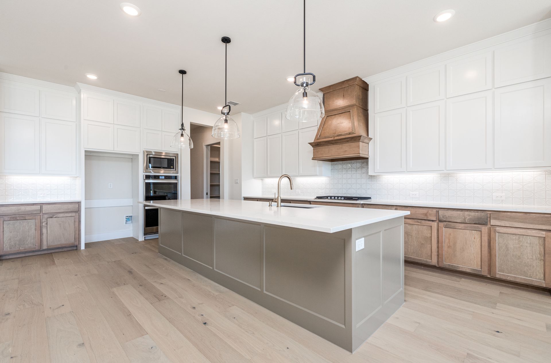 Modern kitchen with white cabinets, gray island, and light wood floors.