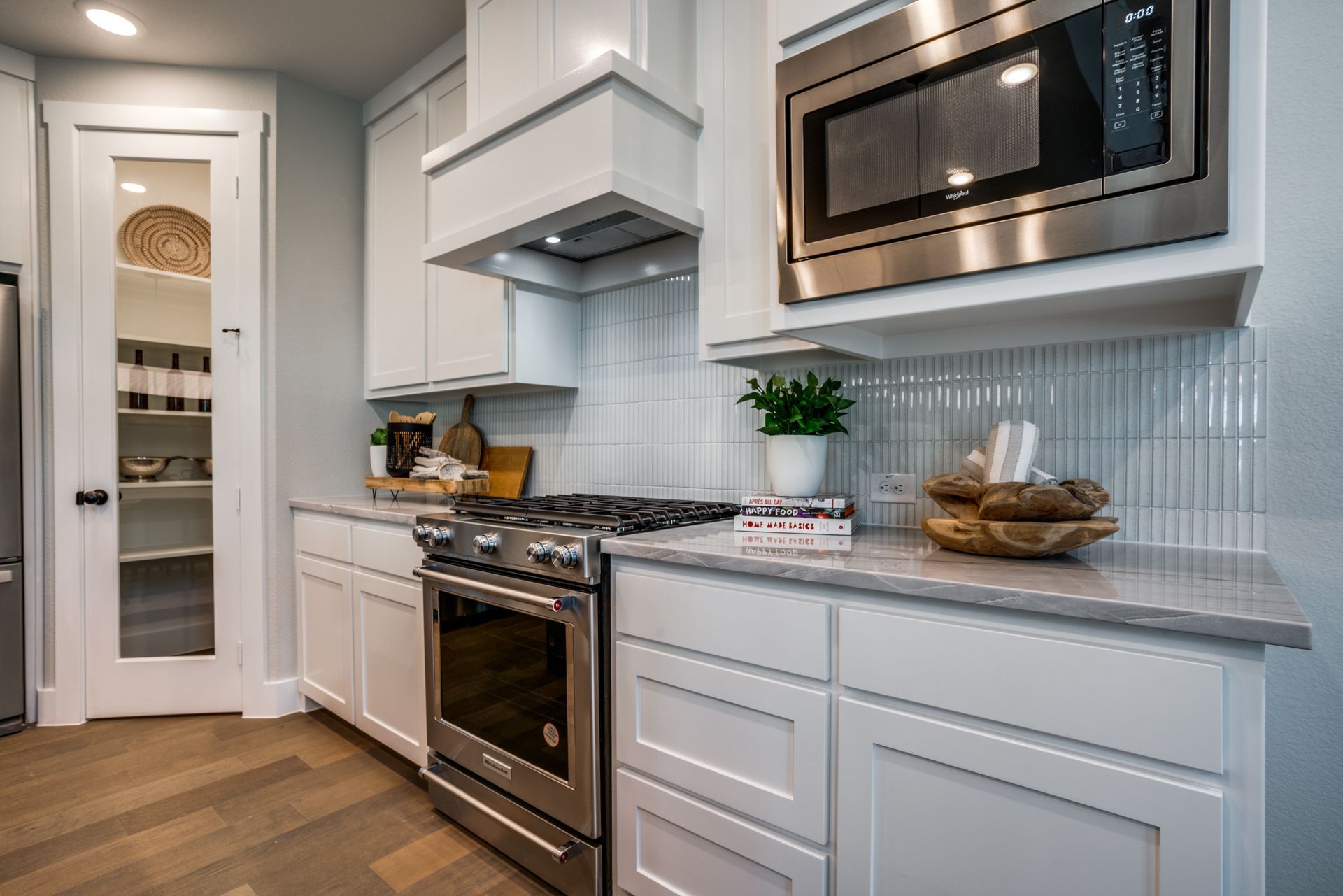 Modern white kitchen with stainless steel appliances, and pantry.