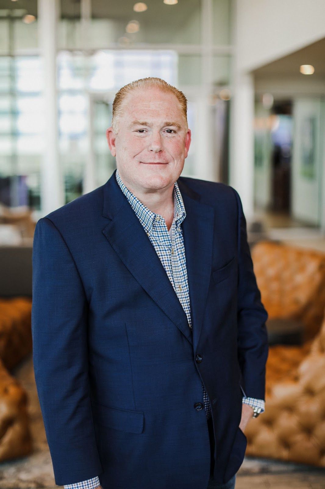 A man in a suit and shirt is standing in a room with his hands in his pockets.