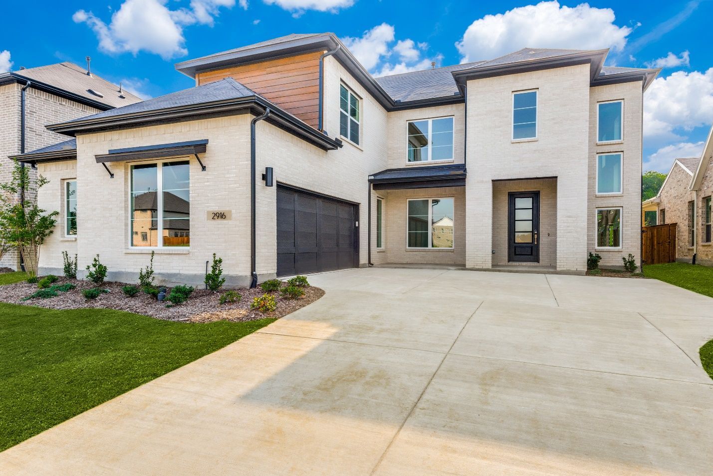 A large white house with a concrete driveway in front of it.