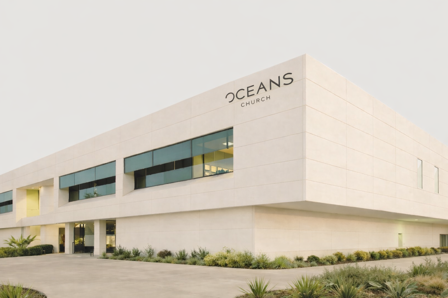 A modern, two-story white building with a flat roof and the text 