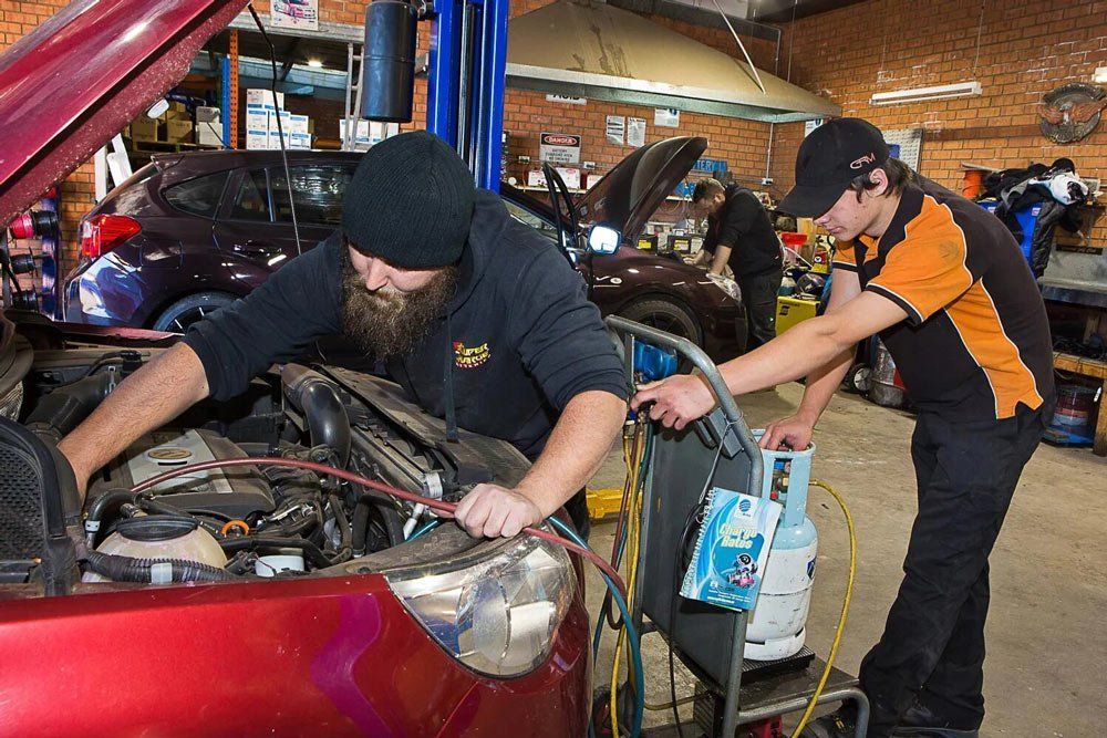 Two Mechanics Working on a Red Car in a Garage — Orange Auto Electrics in Orange, NSW