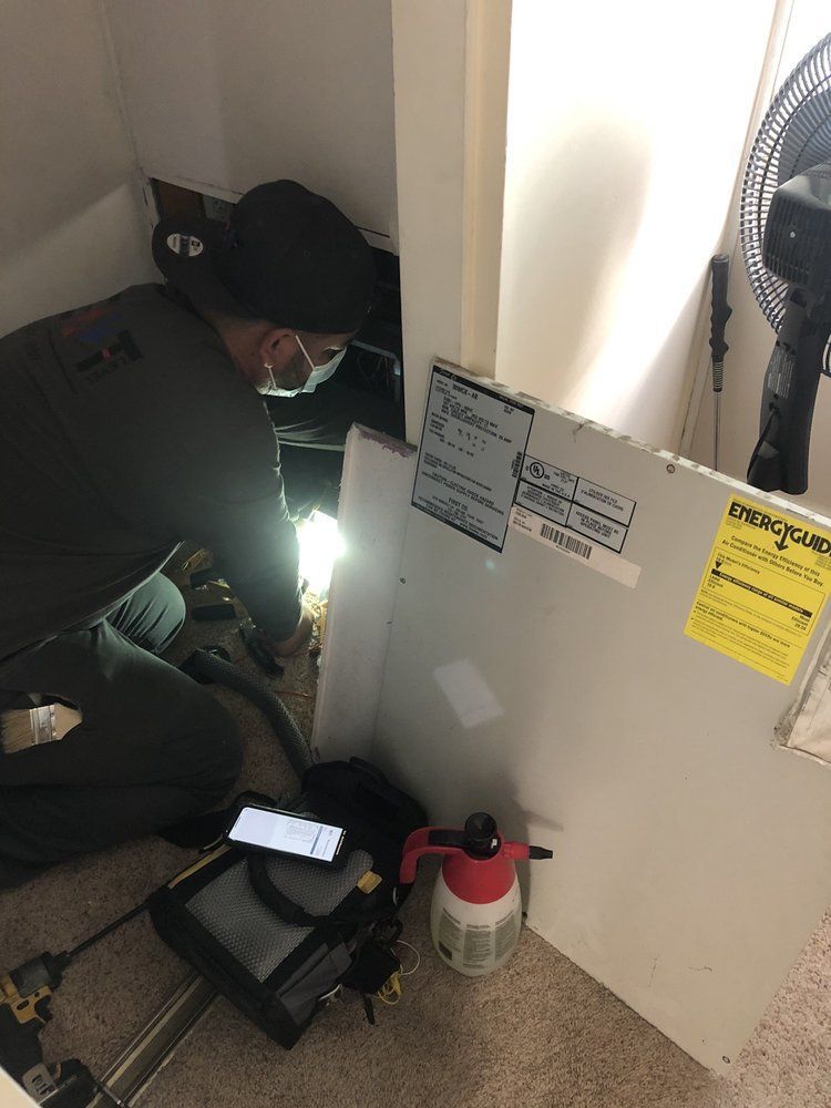 Person in green uniform inspecting a utility area, using a flashlight.