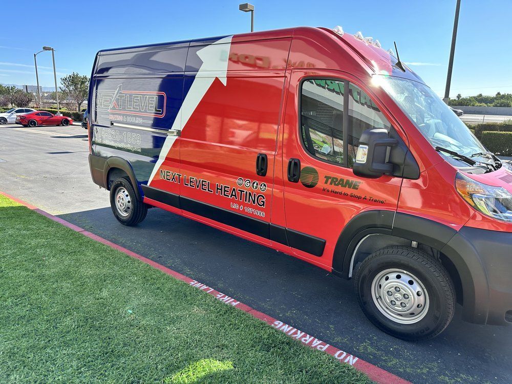 Red and blue service van parked on green grass, advertising plumbing services in Los Angeles.