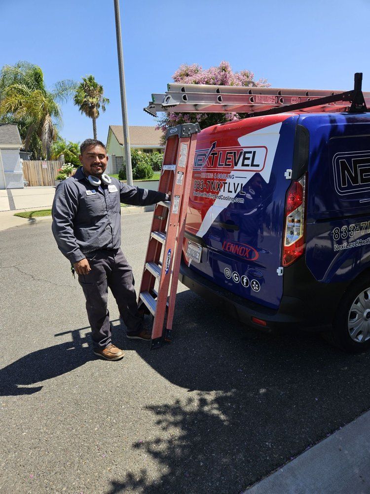 Man in work attire beside a blue and red van with a ladder. Sunny outdoor setting.