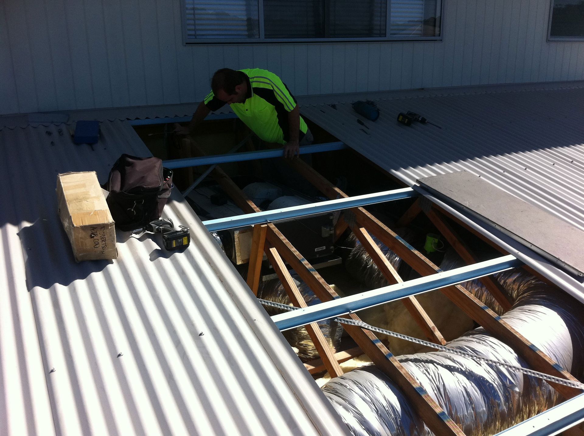 A man either reparing, installing and maintaining ducted air conditioning in the Gold Coast